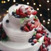 close-up photography of 3-tier vanilla cake with blueberry and strawberry toppings